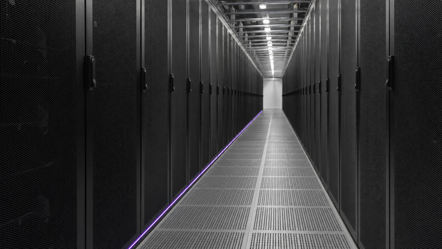 A long cold aisle between identical supercomputer cabinets vanishing toward a bright end wall. Illustrative AI-generated editorial image.